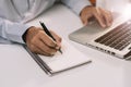 Male businessman use a laptop computer and take notes in the notebook.