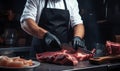 Male butcher expertly slices meat, viewed from the front, on a dark counter