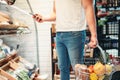 Male buyer with basket and mobile phone in hands