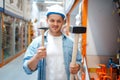 Male buyer holding two hammers in hardware store