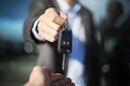 Male car dealer dressed in a suit giving car keys to a female person, focus on hands Royalty Free Stock Photo