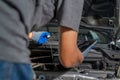 A male car mechanic checking car motor oil and working on repairing the car at car repair garage Royalty Free Stock Photo