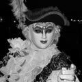 Male carnival goer in traditional costume and mask standing with back to the Grand Canal, gondolas in the background