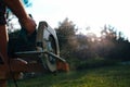 Male carpenter circular saw cuts the board backlit sunset. Close-up view of the tool and flying sawdust Royalty Free Stock Photo
