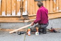 A male carpenter crouched down assembling a piece of wood on a house, outdoors