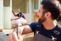 Male Carpenter With Female Apprentice Measuring Wood To Build Outdoor Summerhouse In Garden Royalty Free Stock Photo