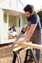 Male Carpenter With Female Apprentice Sawing Wood To Build Outdoor Summerhouse In Garden Royalty Free Stock Photo