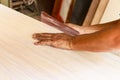 Male carpenter hands sanding the edge of a table manually, indoors