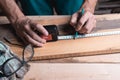 Male carpenter notes with pencil using measuring tape on the Board, marks for saw cut, male hands with pencil and measuring tape c