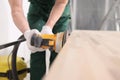 Male carpenter processes wooden table with grinder machine Royalty Free Stock Photo