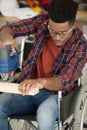 male carpenter in wheelchair using electric jigsaw Royalty Free Stock Photo