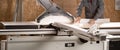 Male carpenter working with sliding panel saw and sawing chipboard at furniture factory workshop. Manufacture and Royalty Free Stock Photo