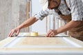 Male carpenter working the wood in carpentry workshop, taking measures on wooden door with a metal square ruler on a wooden door,