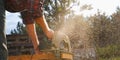 A male carpenter works with a circular saw on the lawn. Close-up view of a working tool. Contrast sunlight with glare scattered in Royalty Free Stock Photo