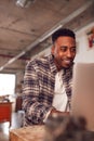 Male Carpenter In Workshop Doing Accounts On Laptop Royalty Free Stock Photo