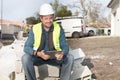 Male Caucasian construction worker sitting with tablet