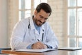 Male Caucasian doctor make notes in medical journal