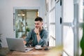 A male caucasian, Handsome Freelancer bearded man in t-shirt taking notes at laptop sitting at desk. freelance concept Royalty Free Stock Photo