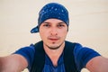 Male Caucasian tourist wearing a bandana makes a selfie at camera