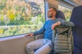Male caucasian traveler rides in a suburban high-speed train with a backpack on the seat, looks out the window enjoying the trip Royalty Free Stock Photo