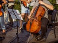 Male cellist playing violoncello in orchestra outdoors