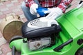 A man Checking the fuel level in lawn mower. A green lawnmower. Gardening. Maintenance of equipment
