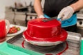 Male chef confectioner making a cake with a cherry. concept production process at home cakes to order customers.