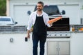 Male chef in cook apron grilling and barbequing salmon fish in garden. Handsome man preparing barbecue salmon fillet Royalty Free Stock Photo