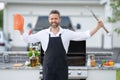 Male chef in cook apron grilling and barbequing salmon fish in garden. Handsome man preparing barbecue salmon fillet Royalty Free Stock Photo