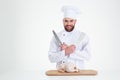 Male chef cook standing with knifes and chicke Royalty Free Stock Photo