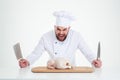 Male chef cook standing with knifes and chicken Royalty Free Stock Photo