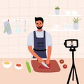 Male chef cooking in the kitchen while recording video using his camera for online video channel. Cook healthy food at home.