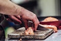 Male Chef Cutting Fresh Salmon on the Wooden Board with Blurred Pan in a Background Royalty Free Stock Photo