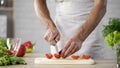 Male chef cutting tomatoes on table for fresh vegetable salad home, weight loss