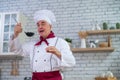 The male chef enjoys the aroma of the soup and tastes it from the ladle in the kitchen