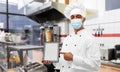 Male chef in face mask with tablet pc at kitchen Royalty Free Stock Photo