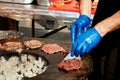 Male chef frying meat burger patties on an open grill