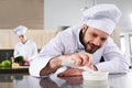 Male chef garnishing dish on restaurant kitchen in front of Royalty Free Stock Photo