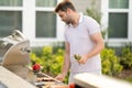 Male chef grilling and barbequing in garden. Barbecue outdoor garden party. Handsome man cook preparing barbecue meat Royalty Free Stock Photo