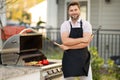 Male chef grilling and barbequing in garden. Barbecue outdoor garden party. Handsome man preparing barbecue meat Royalty Free Stock Photo