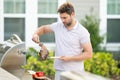 Male chef grilling and barbequing in garden. Barbecue outdoor garden party. Handsome man preparing barbecue meat