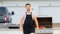 Male chef grilling and barbequing in garden. Barbecue outdoor garden party. Handsome man cook preparing barbecue meat Royalty Free Stock Photo