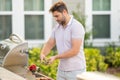 Male chef grilling and barbequing in garden. Barbecue outdoor garden party. Handsome man cook preparing barbecue meat