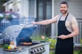 Male chef grilling and barbequing in garden. Barbecue outdoor garden party. Handsome man preparing barbecue meat Royalty Free Stock Photo