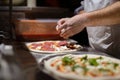 Male chef hands making pizza in the pizzeria kitchen