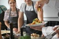 Male chef holding plate with prepared dish during cooking classes