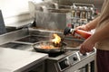 Male chef with manual gas burner cooking food on stove in restaurant kitchen, closeup of hands Royalty Free Stock Photo