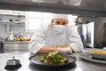 Male chef in mask with food at restaurant kitchen