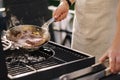 Male chef preparing T-bone steak on carbon steel frying pan outdoor on grill. BBQ concept. Close-up
