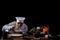 Male chef in a restaurant kitchen wearing white uniform tasting spaghetti with fresh vegetables